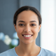 A happy woman in her late 20s smiling, looking directly at the camera, conveying satisfaction and trust.